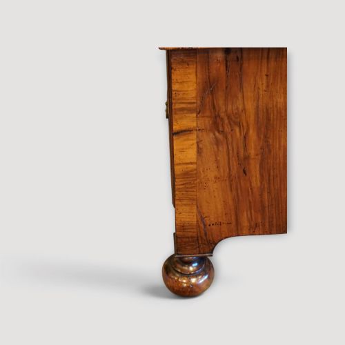 fig 3. An antique Queen Anne walnut chest-on-chest in two sections featuring a multi-drawer configuration, figured grain patterns, brass drop handles, and bun feet.