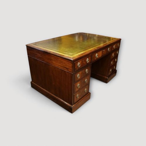 fig 1. A Victorian mahogany partners desk featuring a green leather writing surface, dual pedestals with drawers, and round brass handles.