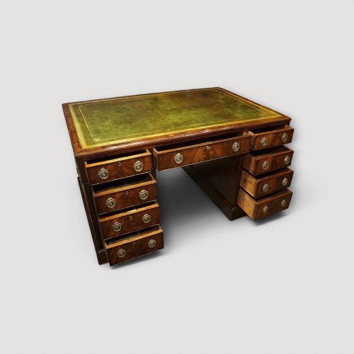fig 2. A Victorian mahogany partners desk featuring a green leather writing surface, dual pedestals with drawers, and round brass handles.