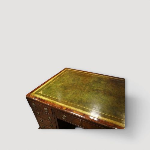 fig 3. A Victorian mahogany partners desk featuring a green leather writing surface, dual pedestals with drawers, and round brass handles.