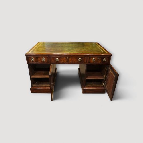 fig 7. A Victorian mahogany partners desk featuring a green leather writing surface, dual pedestals with drawers, and round brass handles.