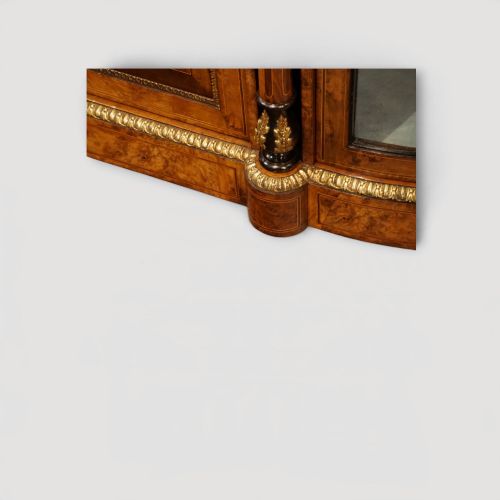 fig 2. A Victorian burr walnut credenza featuring a central marquetry inlaid door flanked by two curved glazed display side cabinets with gilt mounts.