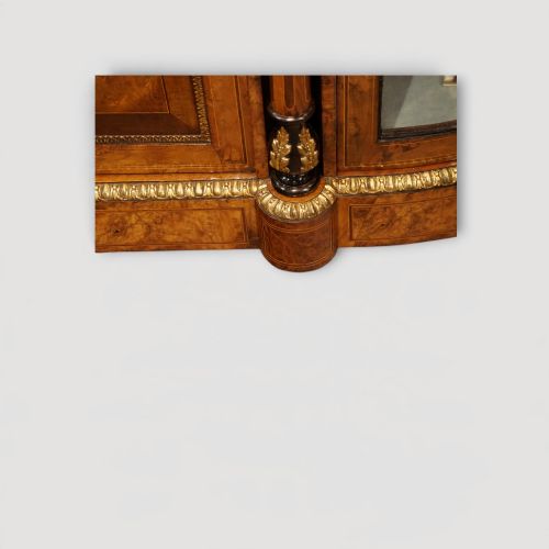 fig 4. A Victorian burr walnut credenza featuring a central marquetry inlaid door flanked by two curved glazed display side cabinets with gilt mounts.
