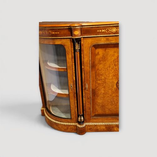 fig 6. A Victorian burr walnut credenza featuring a central marquetry inlaid door flanked by two curved glazed display side cabinets with gilt mounts.