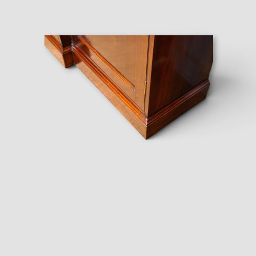 fig 5. An Edwardian mahogany breakfront bookcase featuring an open upper shelving section filled with books and an enclosed lower cupboard base.