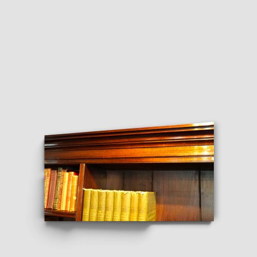 fig 7. An Edwardian mahogany breakfront bookcase featuring an open upper shelving section filled with books and an enclosed lower cupboard base.