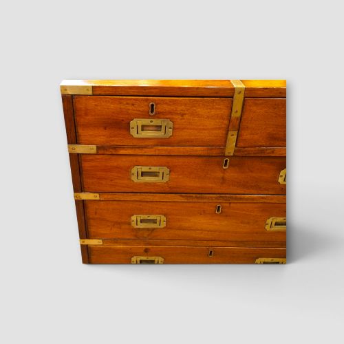 fig 3. A wooden chest of drawers featuring brass corner brackets, flush handles, and two short drawers above three long drawers.
