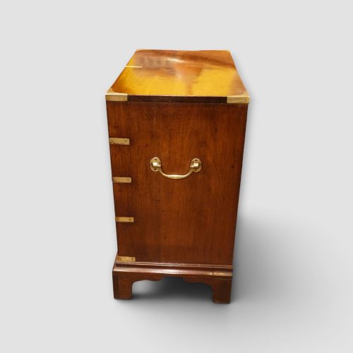 fig 4. A wooden chest of drawers featuring brass corner brackets, flush handles, and two short drawers above three long drawers.