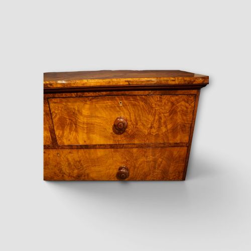 fig 7. A Victorian burr walnut chest of drawers featuring two short drawers over three long drawers with turned walnut knobs and a plinth base.