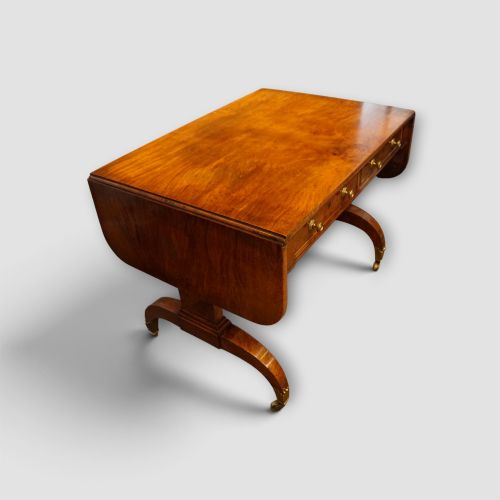 fig 1. A Regency burr satinwood sofa table with drop leaves, two frieze drawers, brass handles, and splayed legs on castors.