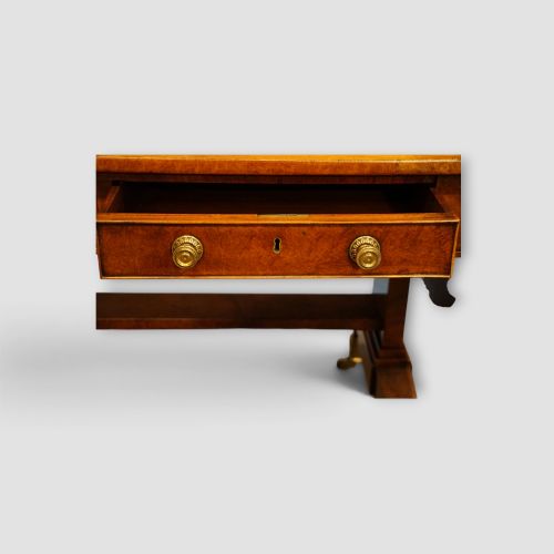 fig 3. A Regency burr satinwood sofa table with drop leaves, two frieze drawers, brass handles, and splayed legs on castors.