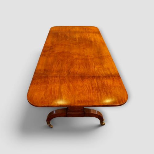 fig 6. A Regency burr satinwood sofa table with drop leaves, two frieze drawers, brass handles, and splayed legs on castors.