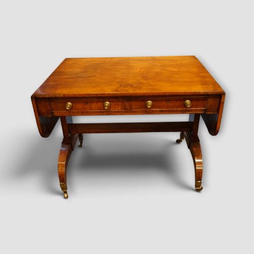 fig 7. A Regency burr satinwood sofa table with drop leaves, two frieze drawers, brass handles, and splayed legs on castors.