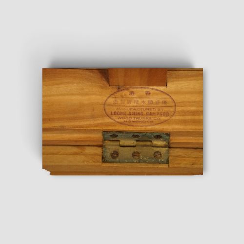 fig 9. A low rectangular warm amber camphor wood campaign trunk featuring brass strap corners, flush brass handles, dual keyholes, and turned legs with castors.