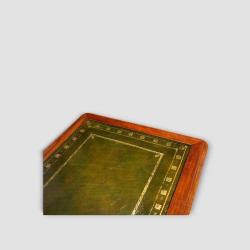 fig 2. An early Victorian mahogany writing table featuring a green leather inset top with gilt tooling, two frieze drawers, a turned stretcher, and end supports.