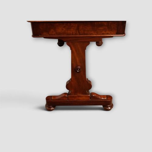 fig 5. An early Victorian mahogany writing table featuring a green leather inset top with gilt tooling, two frieze drawers, a turned stretcher, and end supports.