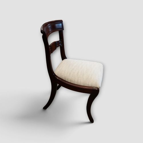 fig 4. A set of eight Regency mahogany dining chairs with neutral cream upholstery, carved back rails, and curved sabre legs.