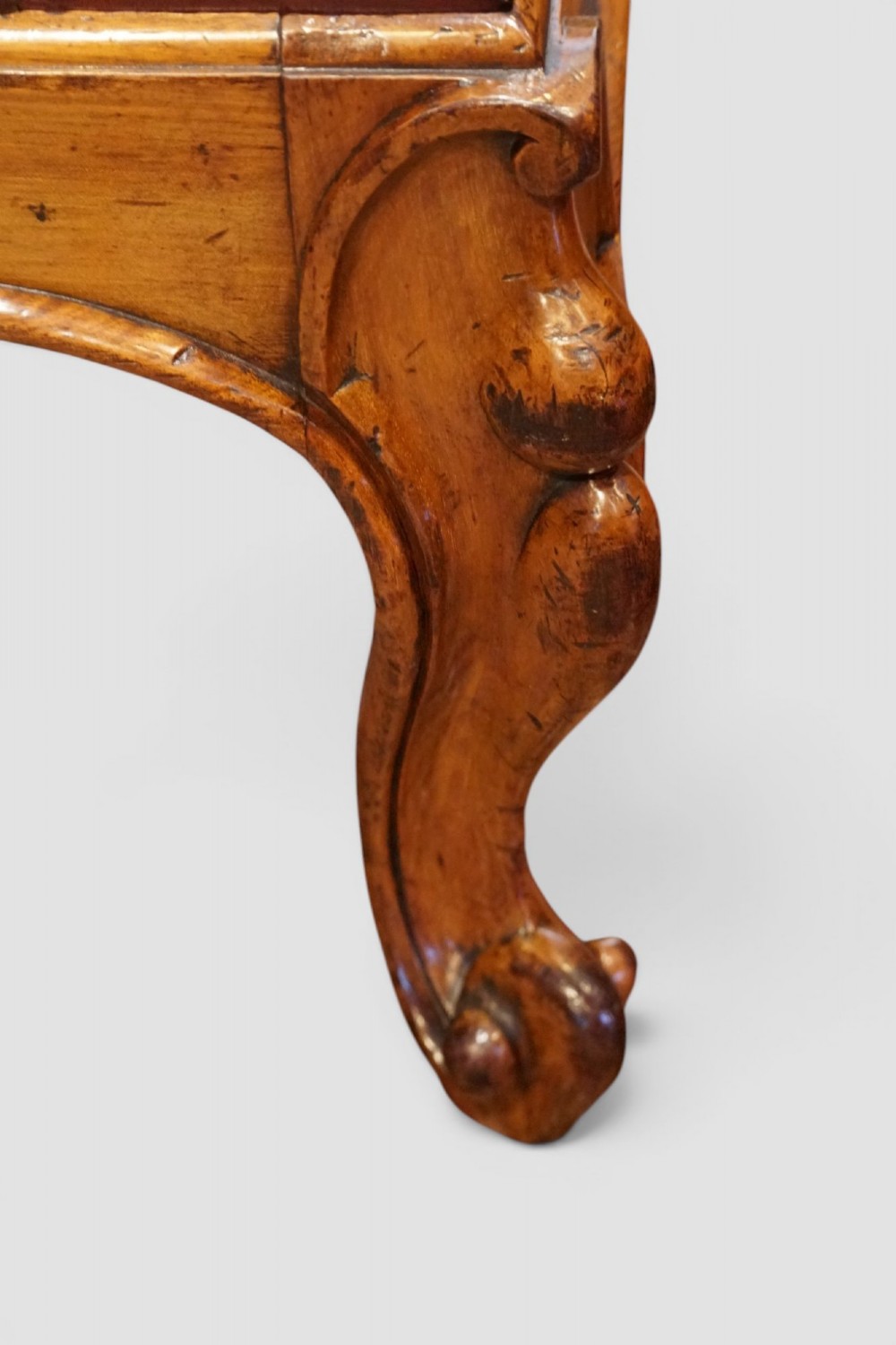 A large Victorian walnut stool featuring deep-buttoned russet red leather upholstery and carved cabriole legs. View VI