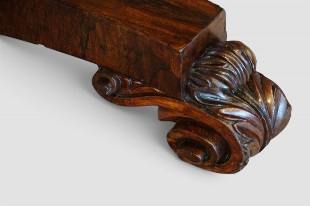 A circular William IV rosewood dining table with a figured veneer top on a central pedestal and tripartite base with scroll feet. View III