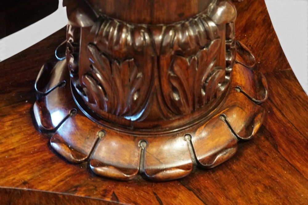 A circular William IV rosewood dining table with a figured veneer top on a central pedestal and tripartite base with scroll feet. View IV