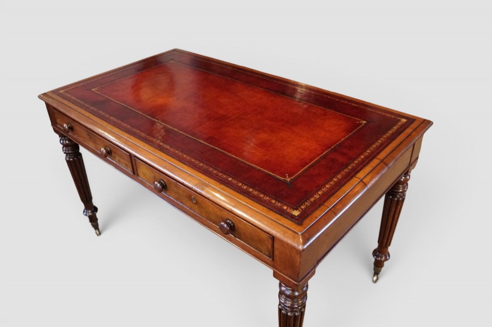 A Victorian mahogany partners writing table with a red leather gold-tooled insert top, frieze drawers, turned reeded legs, and brass castors. View II