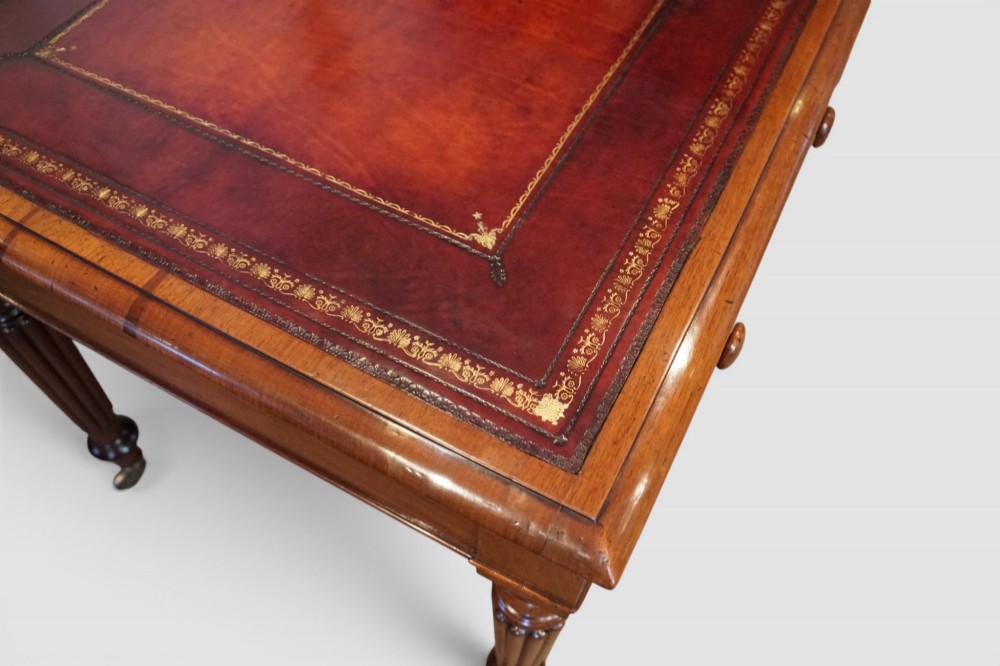 A Victorian mahogany partners writing table with a red leather gold-tooled insert top, frieze drawers, turned reeded legs, and brass castors. View IV