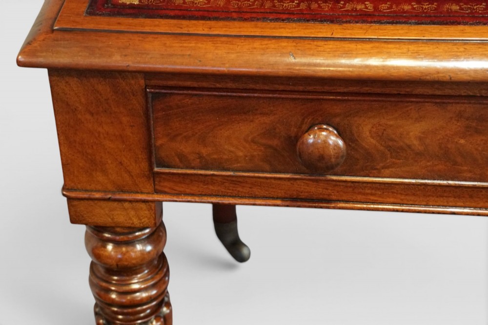 A Victorian mahogany partners writing table with a red leather gold-tooled insert top, frieze drawers, turned reeded legs, and brass castors. View VII