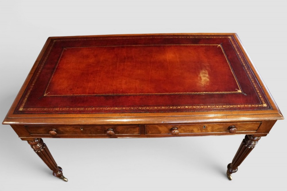 A Victorian mahogany partners writing table with a red leather gold-tooled insert top, frieze drawers, turned reeded legs, and brass castors. View VIII