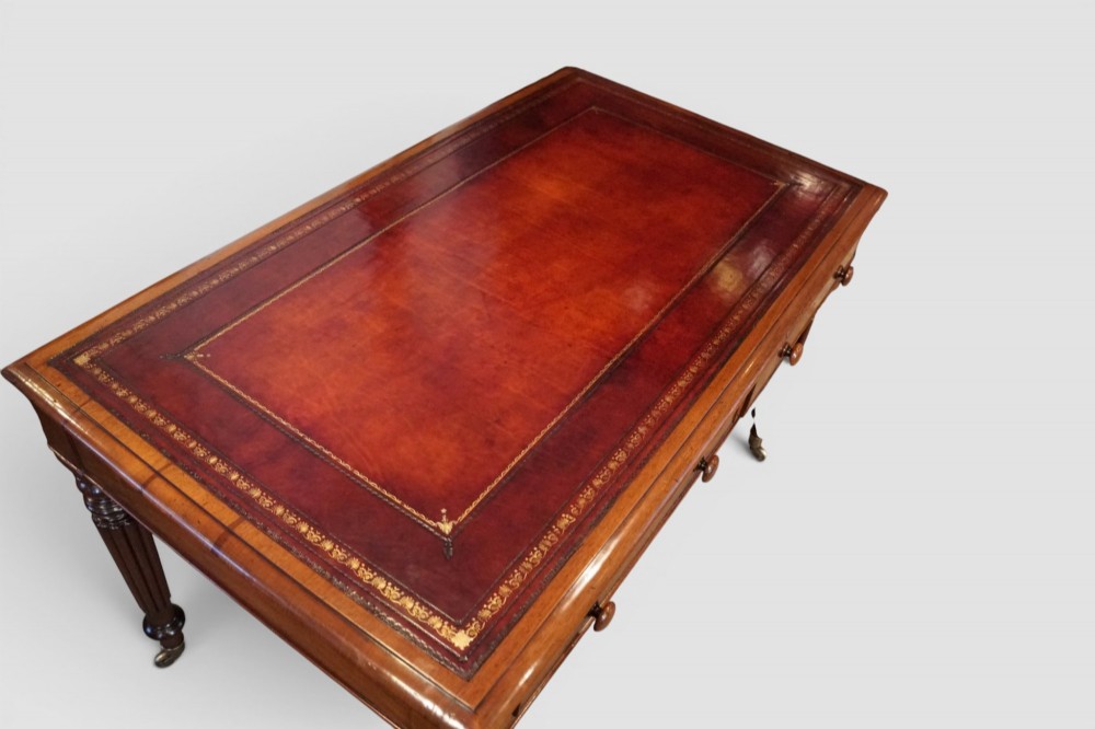 A Victorian mahogany partners writing table with a red leather gold-tooled insert top, frieze drawers, turned reeded legs, and brass castors. View X