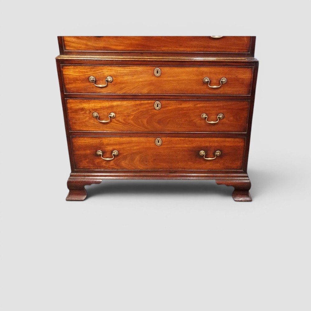 A tall George III mahogany chest-on-chest featuring a carved blind fretwork cornice, brass swan-neck handles, and bracket feet. View III