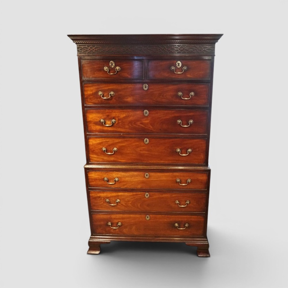 A tall George III mahogany chest-on-chest featuring a carved blind fretwork cornice, brass swan-neck handles, and bracket feet. View VI