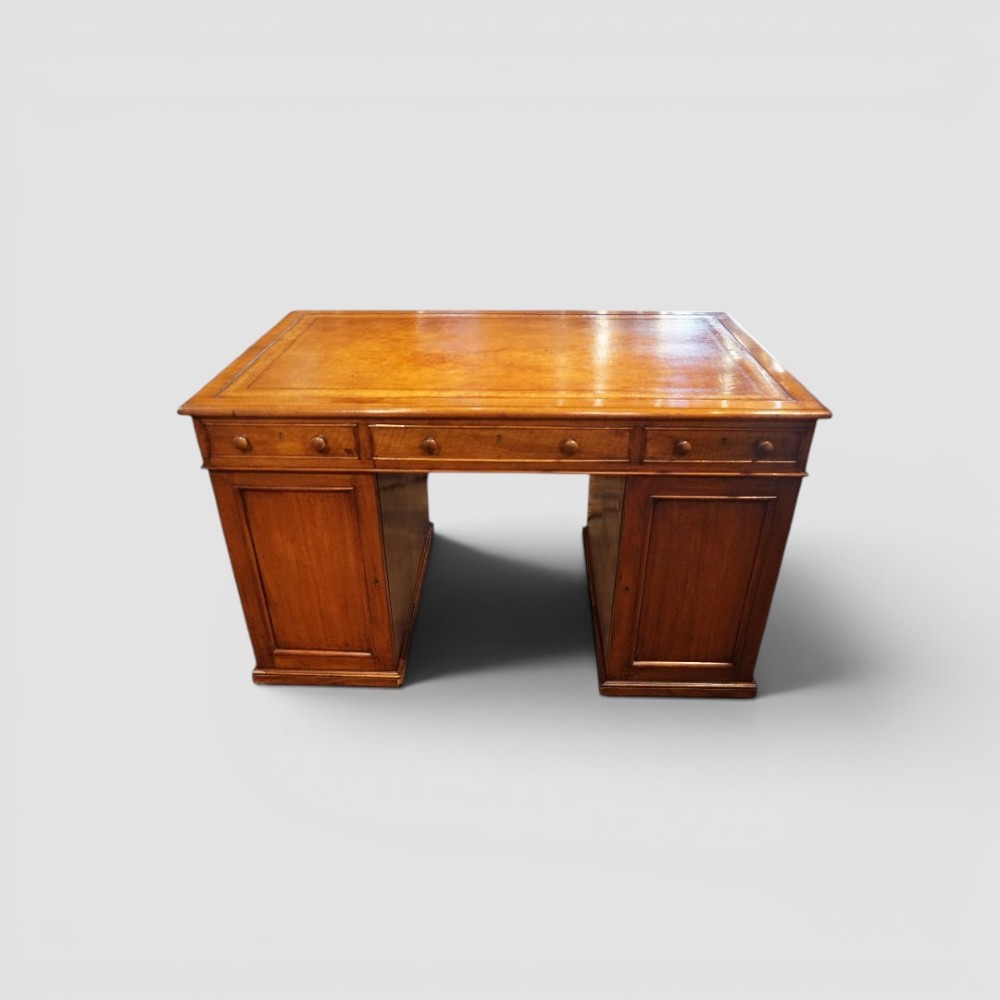 A Victorian mahogany partners desk featuring a tooled leather writing surface, twin pedestals, and an eleven-drawer front configuration with turned wooden knobs. View IV