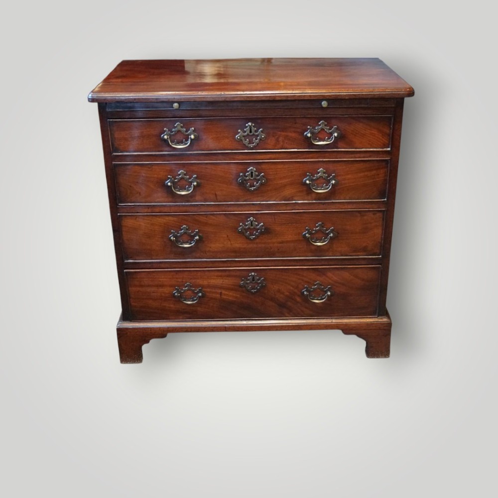 A compact George III mahogany bachelors chest featuring four graduated drawers, brass handles, a pull-out brushing slide, and bracket feet. View II