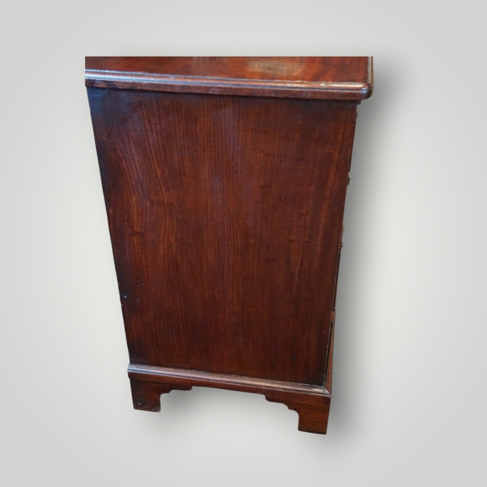 A compact George III mahogany bachelors chest featuring four graduated drawers, brass handles, a pull-out brushing slide, and bracket feet. View IV
