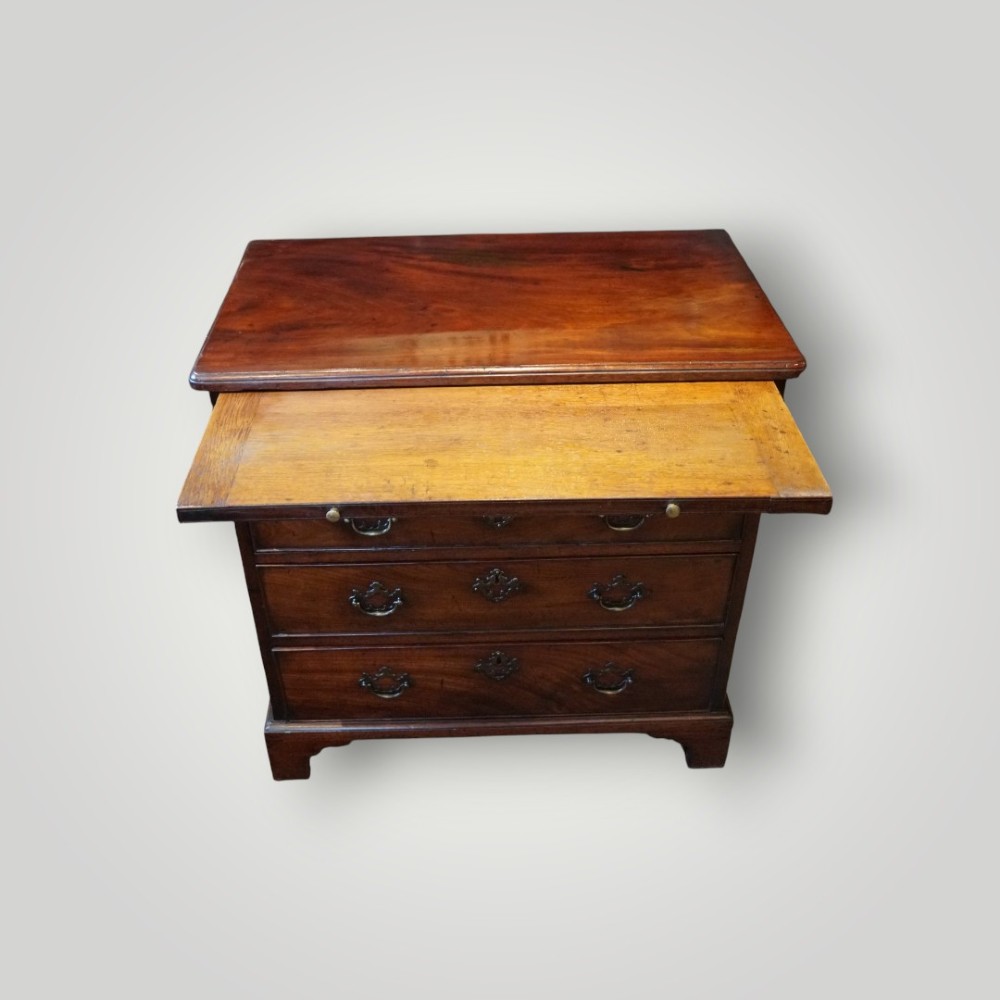 A compact George III mahogany bachelors chest featuring four graduated drawers, brass handles, a pull-out brushing slide, and bracket feet. View V