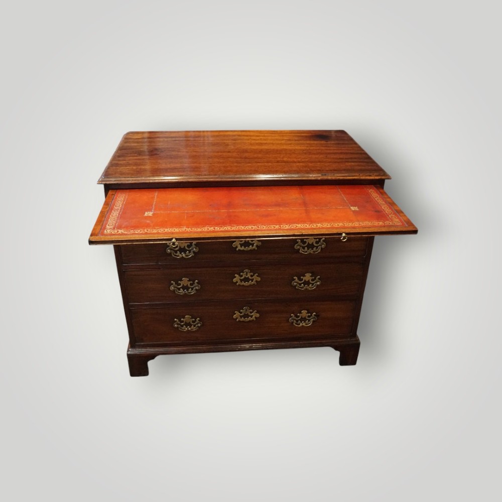 A George III mahogany bachelors chest featuring a top brushing slide, graduated drawers with pierced brass handles, and bracket feet. View VIII