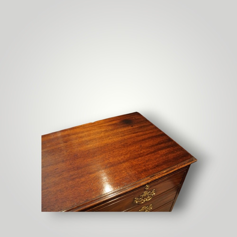 A George III mahogany bachelors chest featuring a top brushing slide, graduated drawers with pierced brass handles, and bracket feet. View IX