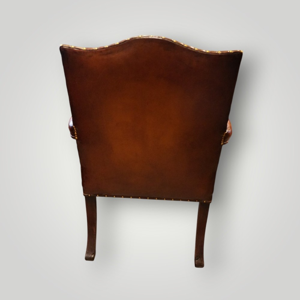 A Georgian style Gainsborough armchair upholstered in warm tan leather with brass stud detailing and carved mahogany legs. View XI