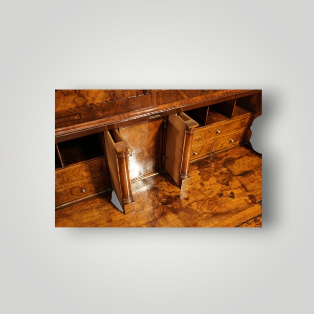 A George I walnut bureau bookcase featuring glazed upper doors housing books, a slant-front writing flap, and lower drawers with brass drop handles. View XIII