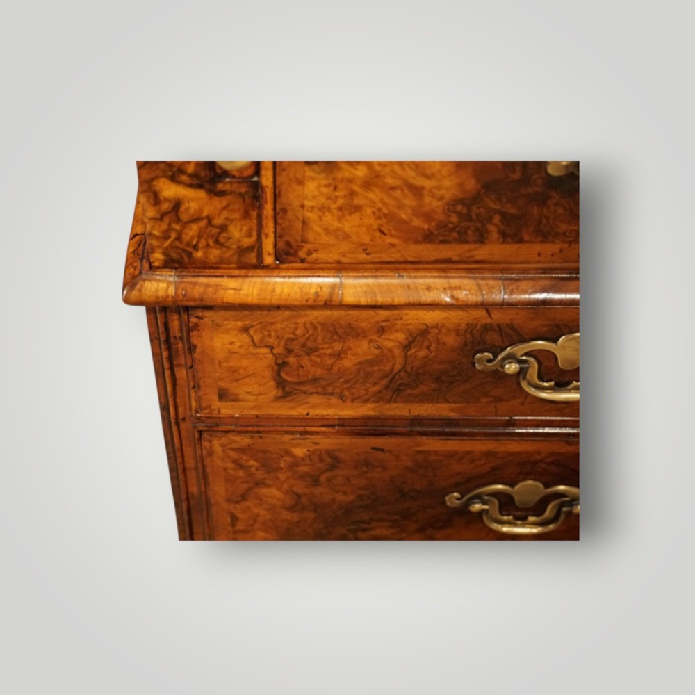 A George I walnut bureau bookcase featuring glazed upper doors housing books, a slant-front writing flap, and lower drawers with brass drop handles. View XV