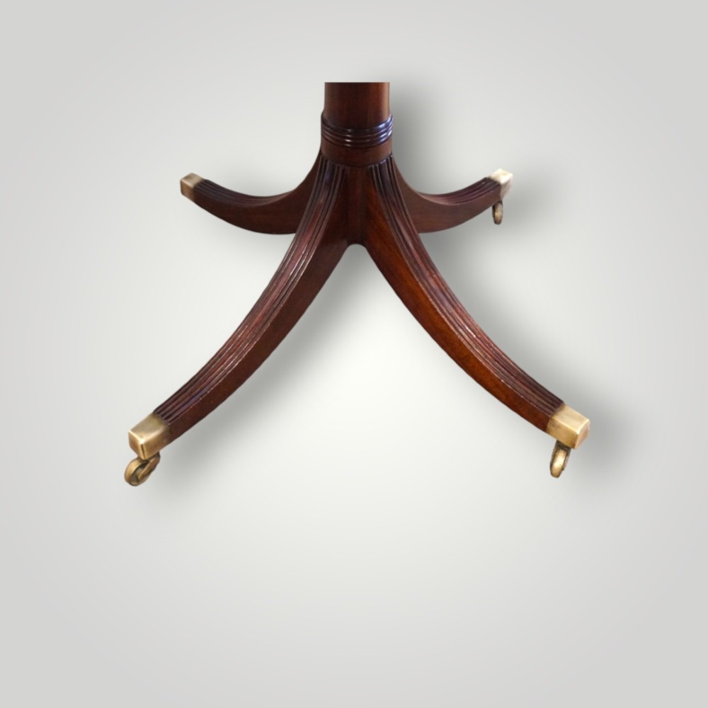 A polished mahogany twin pillar dining table featuring rounded corners, two turned central pedestals, and splayed legs resting on brass castors. View II