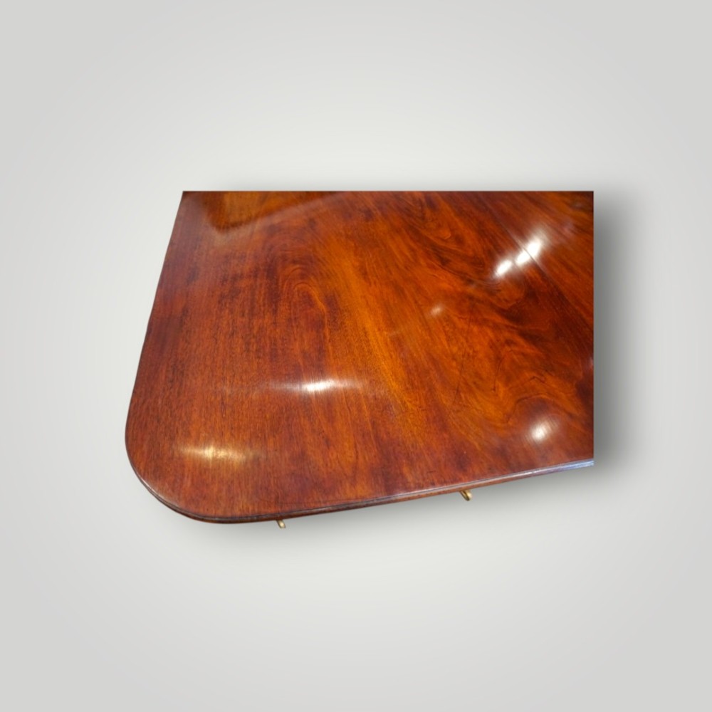 A polished mahogany twin pillar dining table featuring rounded corners, two turned central pedestals, and splayed legs resting on brass castors. View VIII