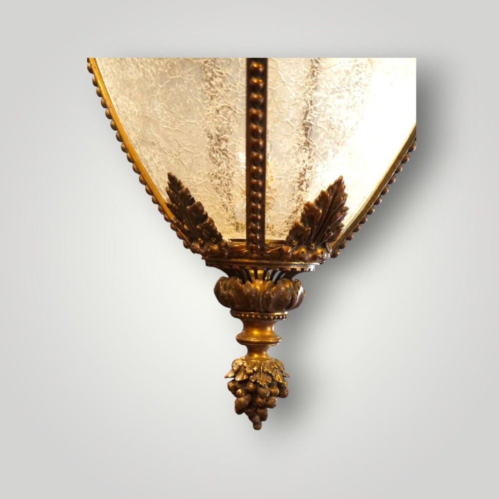 A nineteenth-century gilt bronze hall lantern featuring a tapered glass vessel, acanthus leaf canopy, and decorative drapery swags. View IX