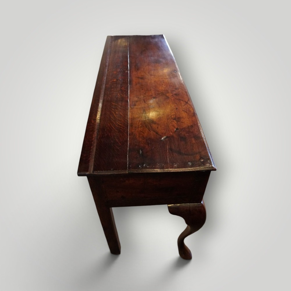 A Georgian oak dresser base featuring two wide drawers with decorative brass handles and four cabriole legs with pad feet. View VI