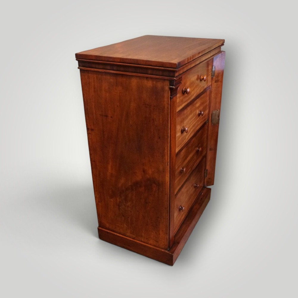 A Victorian warm brown mahogany Wellington chest featuring four stacked drawers with turned wooden handles and a side locking bar. View VII
