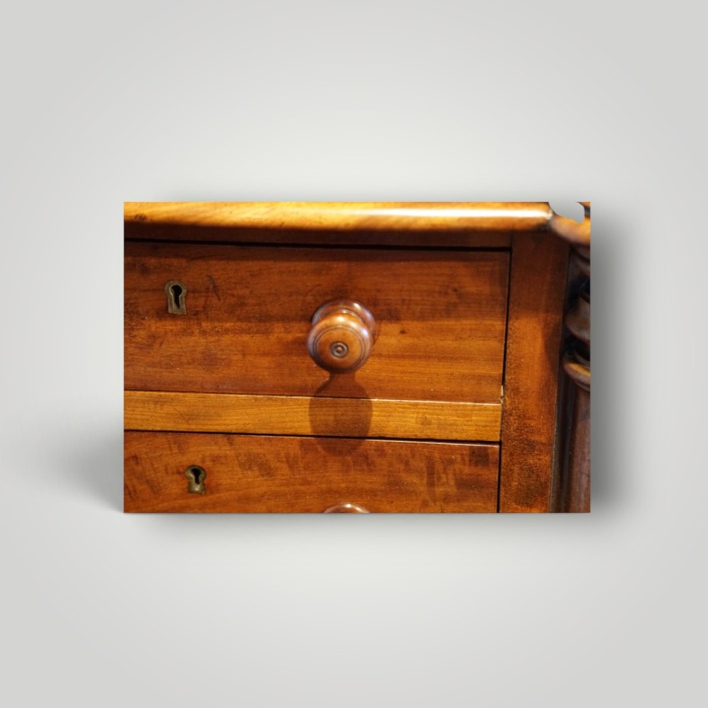 A matching pair of narrow Victorian mahogany bedside chests featuring five graduated drawers with turned side columns on plinth bases. View VI