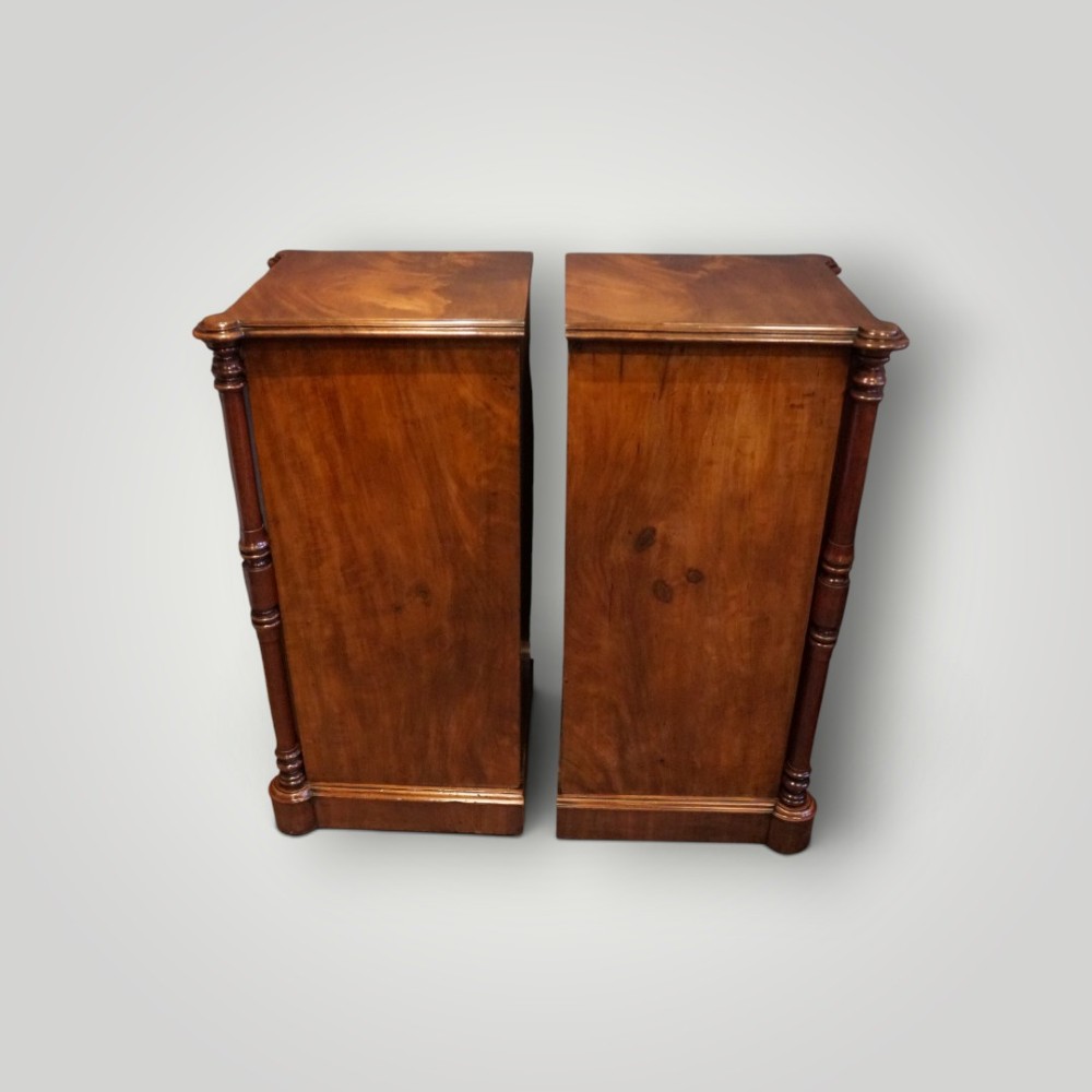 A matching pair of narrow Victorian mahogany bedside chests featuring five graduated drawers with turned side columns on plinth bases. View VII