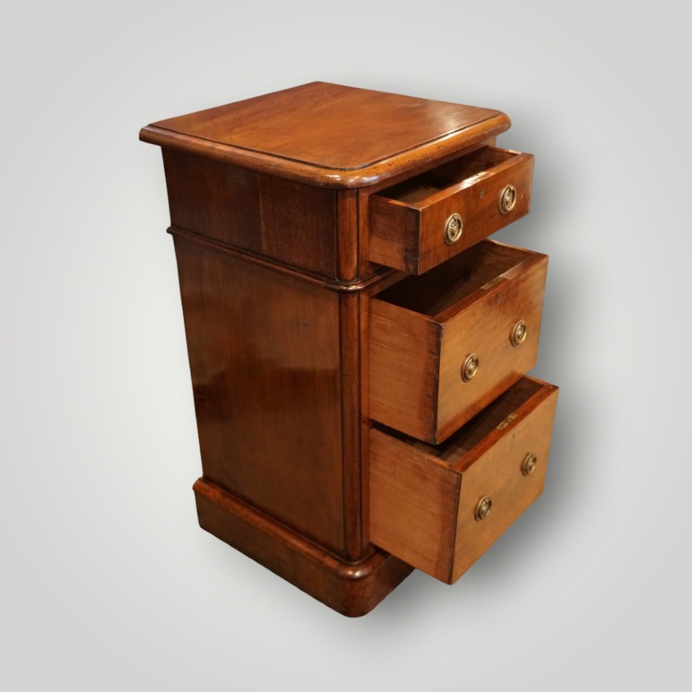 A pair of matching Victorian mahogany bedside chests, each featuring three drawers with brass ring handles and a solid plinth base. View VI