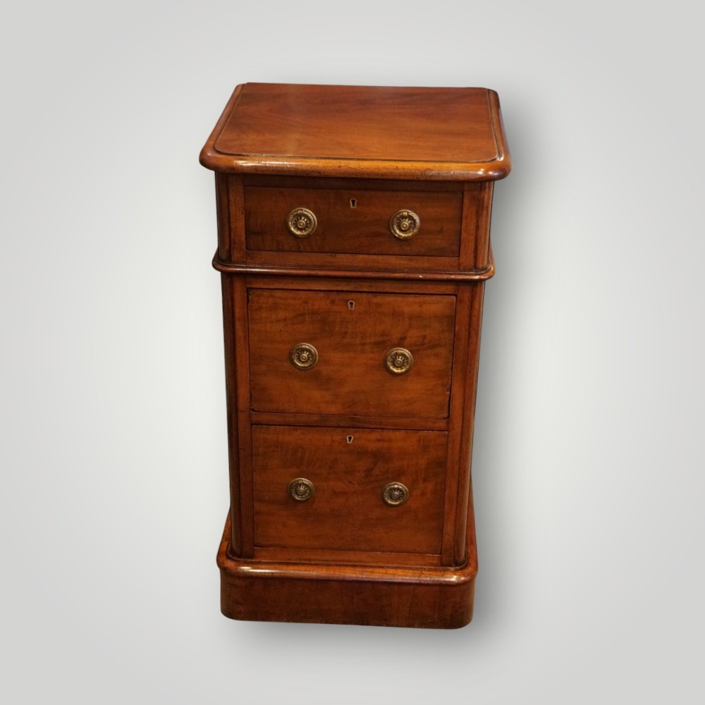 A pair of matching Victorian mahogany bedside chests, each featuring three drawers with brass ring handles and a solid plinth base. View VII