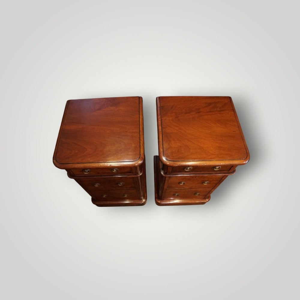 A pair of matching Victorian mahogany bedside chests, each featuring three drawers with brass ring handles and a solid plinth base. View VIII